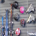 Ett väggmonterat Garageinredningssystem rymmer cykelhjälmar, rullskridskor, skidor, skidstavar och en trådkorg, allt prydligt organiserat på horisontella lameller.