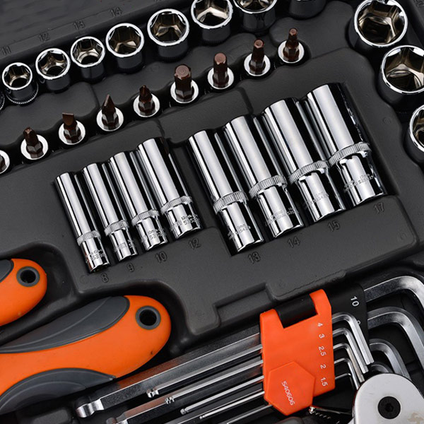 En närbild av en verktygssats i ett svart fodral, med olika kromade hylsor, orange handtagsskruvmejslar och en uppsättning sexkantnycklar med en röd hållare. Verktygen är snyggt organiserade i sina avsedda platser.