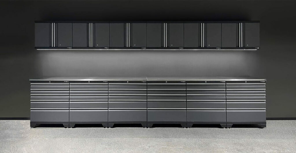 Ett elegant, modernt garageförvaringssystem med en lång rad mattsvarta underskåp med horisontella handtag och matchande överskåp monterade på en mörk vägg. Uppställningen är väl upplyst, vilket framhäver den minimalistiska designen.