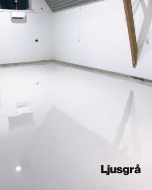 Ett nästan tomt rum med vita väggar och ett glansigt, ljusgrått Epoxigolv PRO-paket-golv. Synliga takbjälkar och fönster syns. Ordet ”Ljusgrå” står i det nedre högra hörnet.