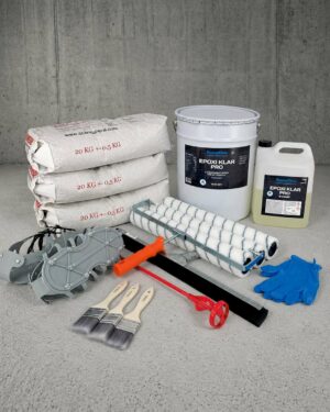 Epoxigolv PRO färgsandspaketet innehåller påsar med betongblandning, penslar, rollers, en blandningsspade, klubba, handskar, epoxi i en kanna och hink samt metallverktyg uppställda på ett betonggolv.